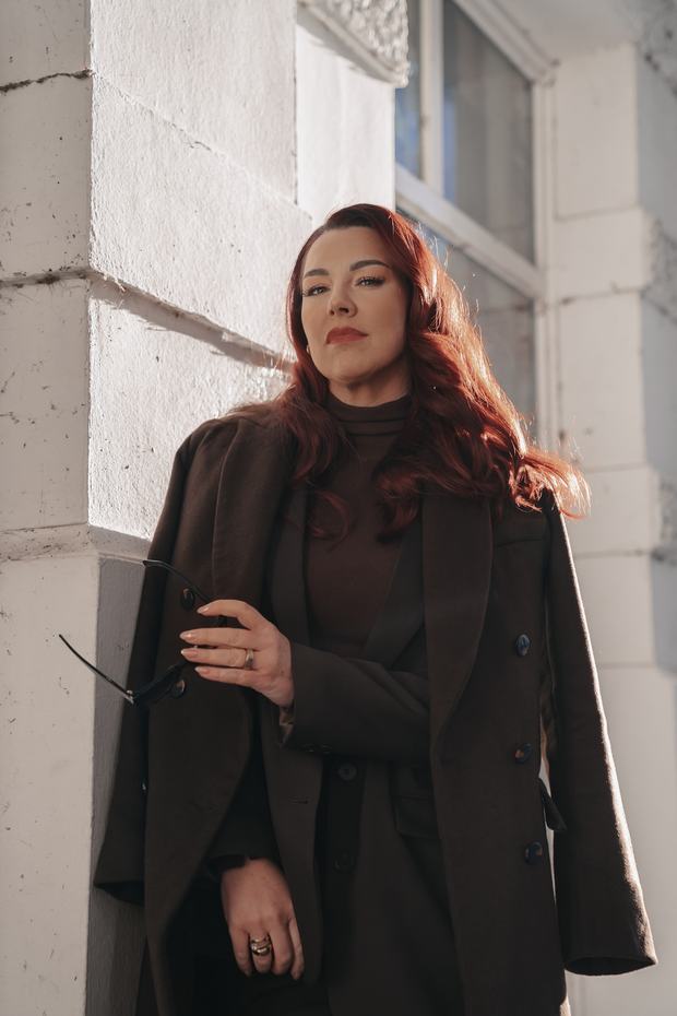 Corinna Moldenhauer im dunklen Mantel an einer hellen Hauswand